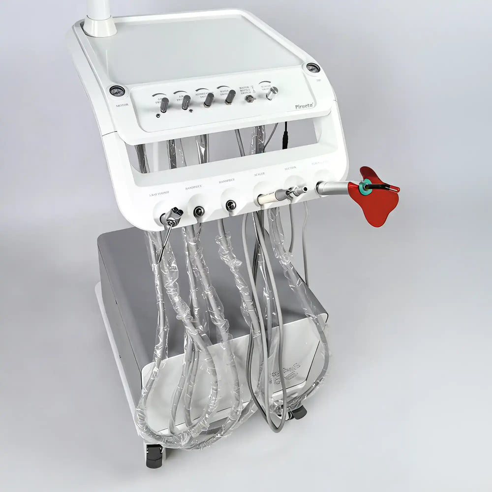 Close-up of the veterinary oral surgery instrument tray, featuring clearly labeled control knobs, high-speed handpiece tubing, scaler, and curing light
